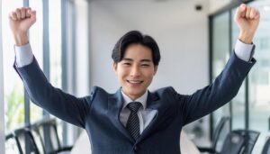 オフィスでガッツポーズをする若い男性（ストライプスーツ）