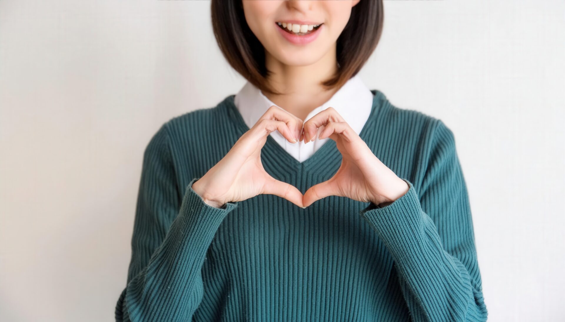 ハートマークを作る笑顔の若い女性（グリーントップス・クローズアップ）