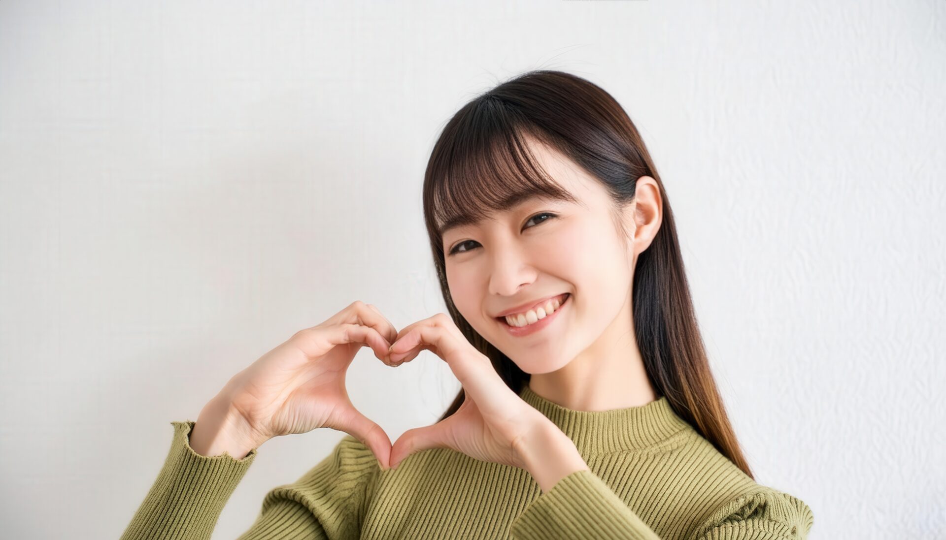 ハートマークを作る若い女性（ライトグリーントップス）