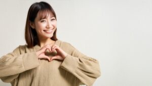 ハートマークを作る若い女性（ベージュトップス）
