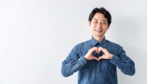 白背景でハートマークを作る男性（ストライプシャツ）