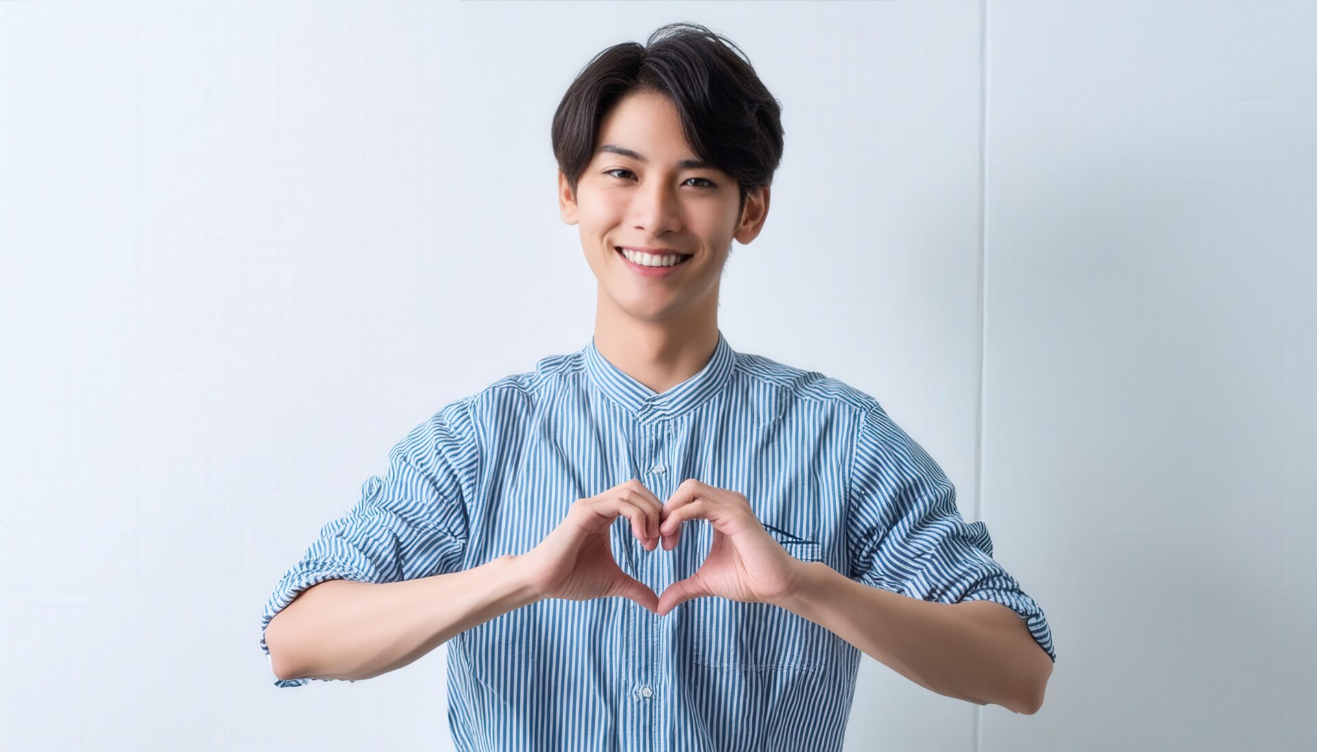白背景でハートマークを作る若い男性（ストライプシャツ）