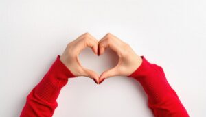 白背景でハートマークを作る手（レッドトップス）