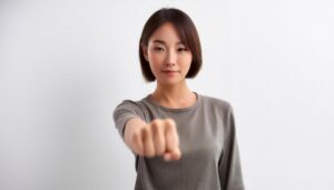 白背景で拳を突き出す若い女性（ショートヘア）