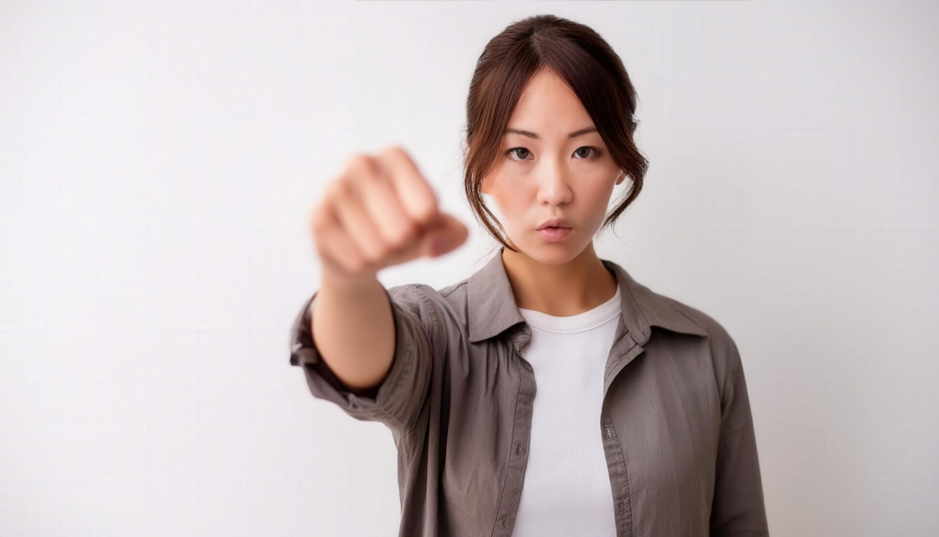 白背景で拳を突き出す若い女性（アップヘア）