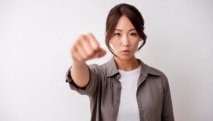 白背景で拳を突き出す若い女性（アップヘア）