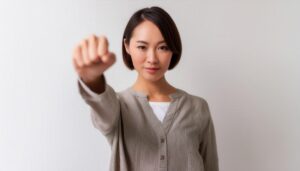 白背景で拳を突き出す若い女性（ショートヘア）