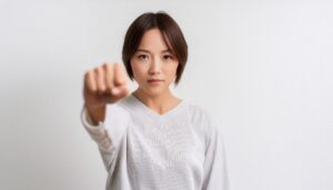 白背景で拳を突き出す若い女性（ショートヘア）