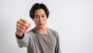 白背景で拳を突き出す若い男性（ショートヘア）