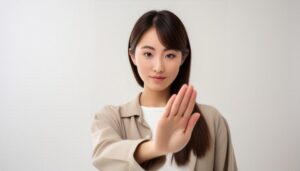 白背景で片手を突き出す若い女性（前髪あり）