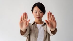 白背景で両手を突き出す若い女性（ポニーテール）