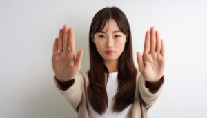 白背景で両手を突き出す若い女性（セミロングヘア）