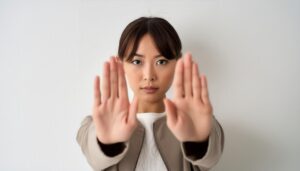 白背景で両手を突き出す若い女性（前髪あり）