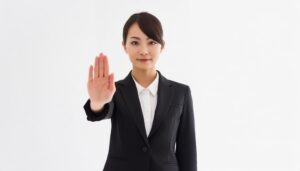 白背景で手のひらを前に突き出す若い女性