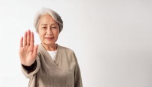 白背景でストップのジェスチャーをするシニア女性