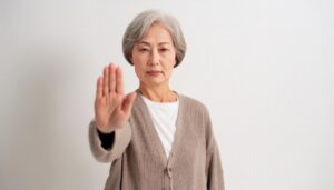 白背景で拒否の姿勢を見せるシニア女性
