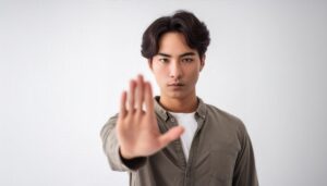 白背景で拒否の姿勢を見せる若い男性（グリーンシャツ）