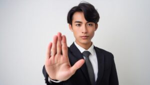 白背景で制止を示す若い男性（スーツとネクタイ）