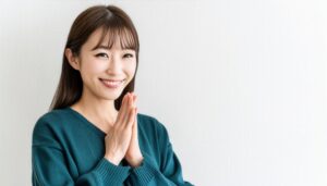 白背景で合掌して微笑む若い女性
