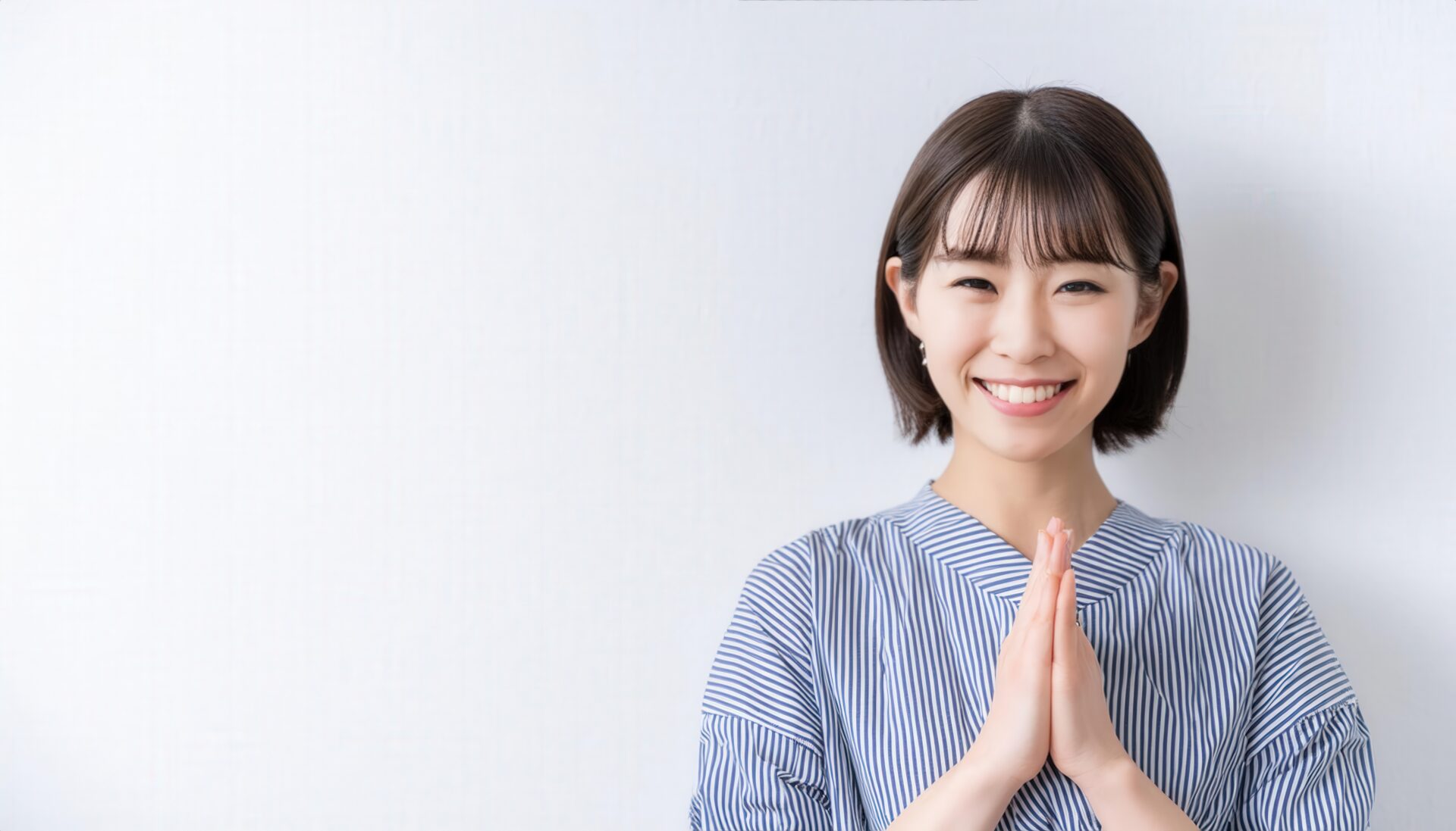 白背景で祈りのポーズをとる若い女性