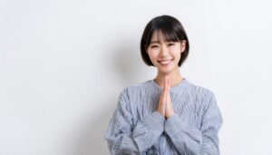 白背景で手を合わせる若い女性（ストライプシャツ）