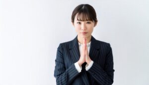 白背景で合掌する若い女性（スーツ）
