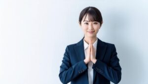 白背景で手を合わせる若い女性（スーツ）