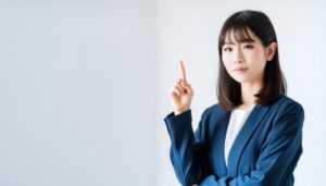 白背景で人差し指を立てる若い女性（スーツ）