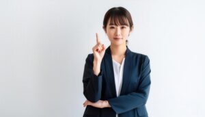 白背景で人差し指を立てる若い女性（スーツ）