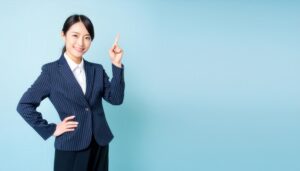水色背景で人差し指を立てる笑顔の若い女性