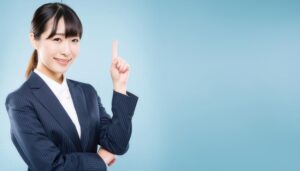 水色背景で指をさす笑顔の若い女性