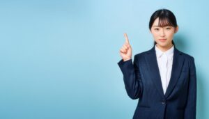 淡い青色背景で指をさす笑顔の若い女性