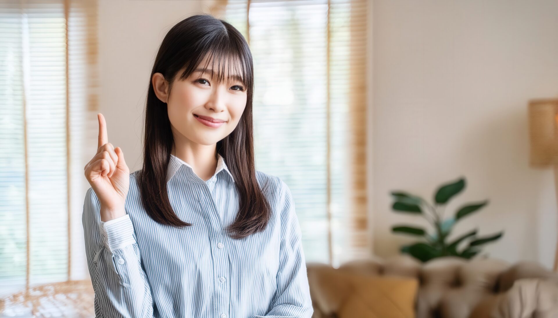 室内で人差し指を立てる笑顔の若い女性