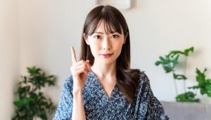 室内で指をさす若い女性（和柄風トップス）