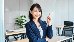 オフィスでストライプのスーツを着て人差し指を立てる笑顔の若い女性