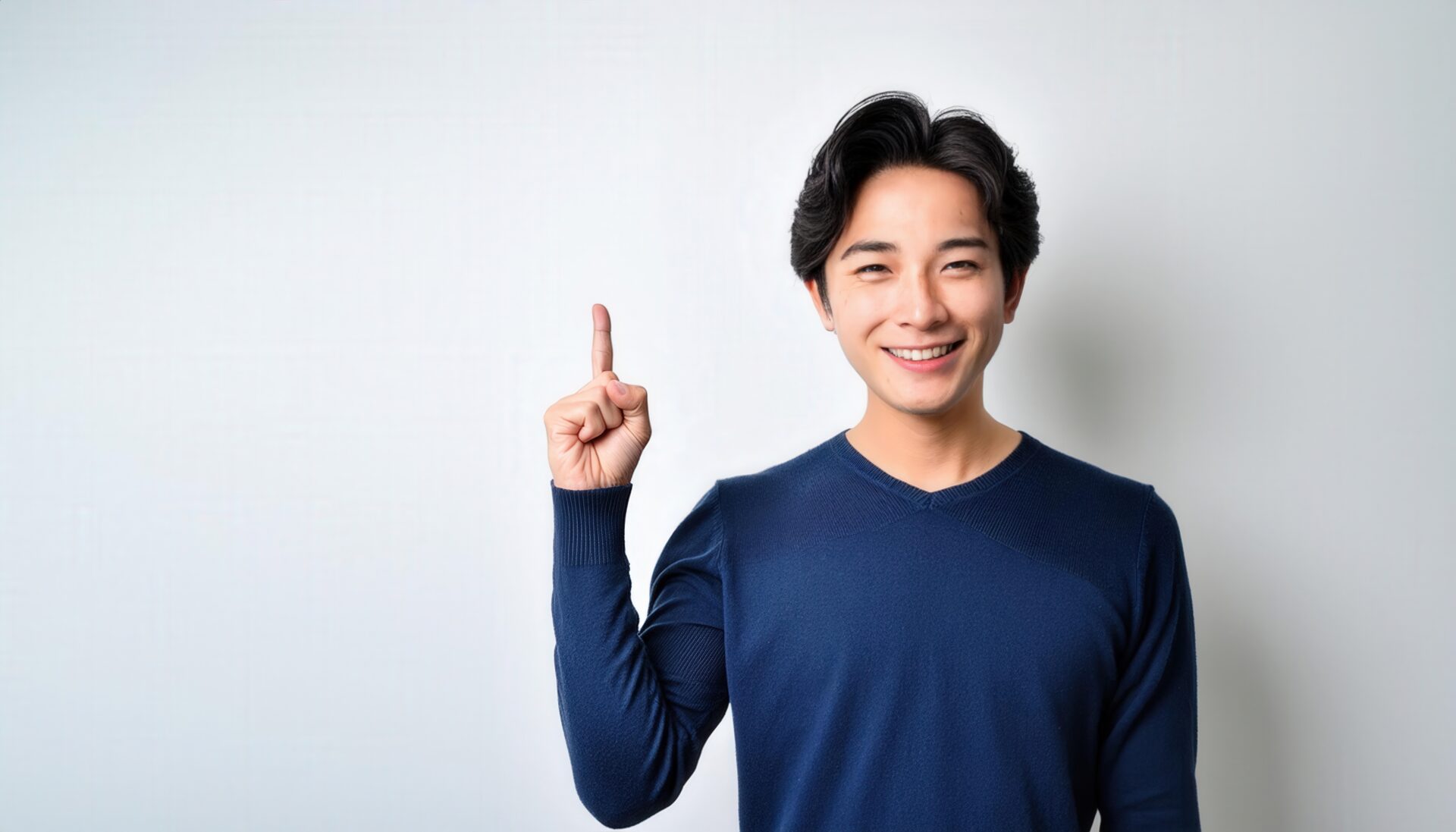 白背景で人差し指を立てる笑顔の若い男性