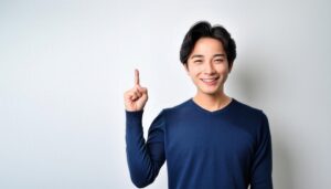 白背景で人差し指を立てる笑顔の若い男性