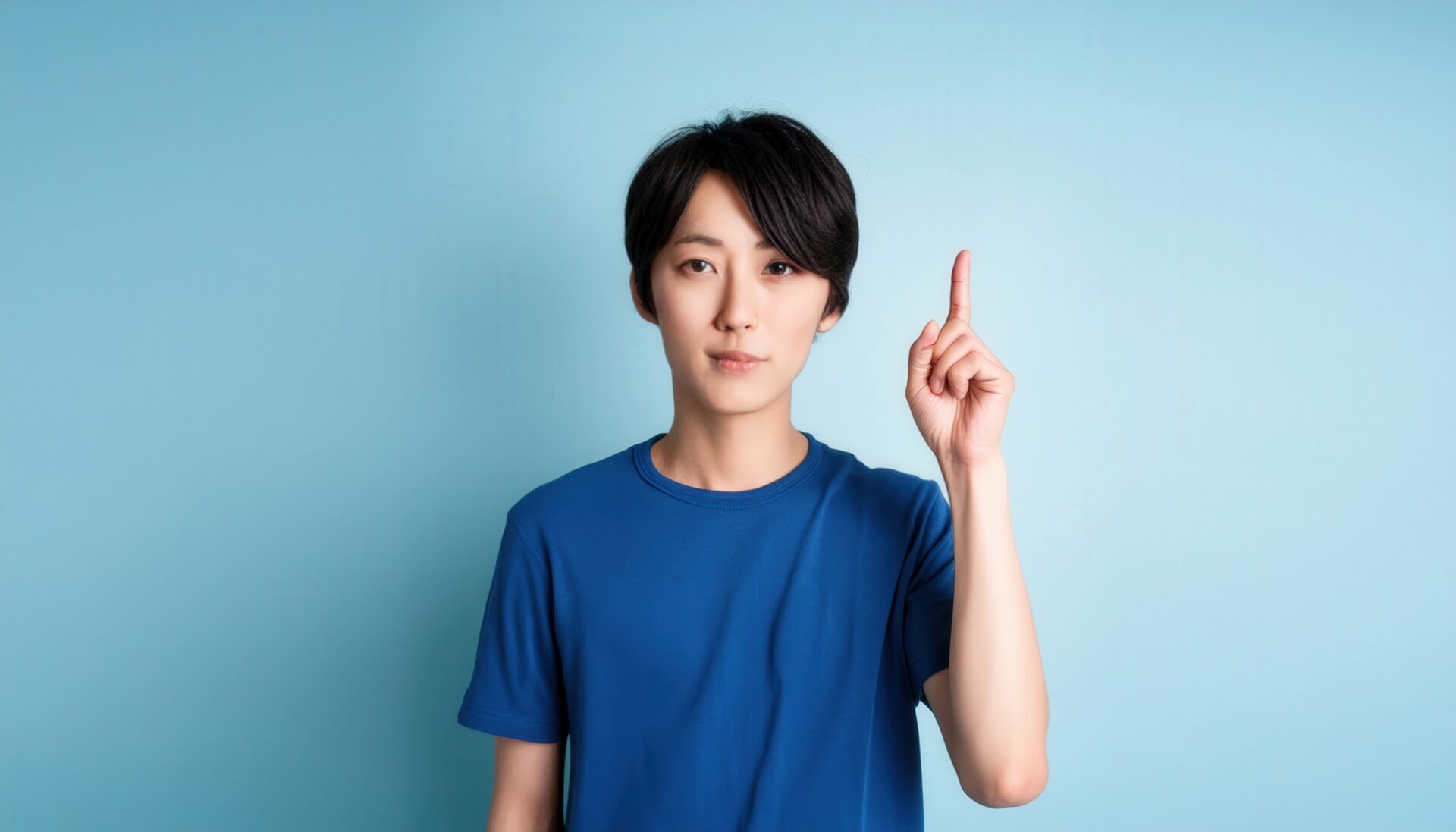 水色背景で人差し指を立てる若い男性（青Tシャツ）