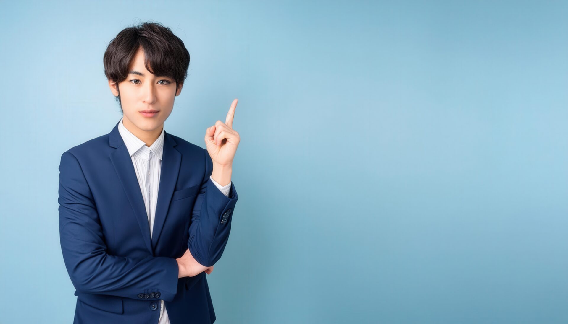 水色背景で人差し指を立てる若い男性（スーツスタイル）