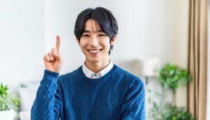 セーターを着た若い人が指をさす