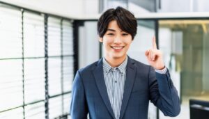 スーツ姿の若い人が指をさす