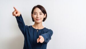 ネイビーブラウスを着た若い人が両手で指をさす