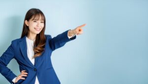 水色の背景でスーツ姿の若い人が指をさす