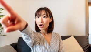 室内でストライプのトップスを着た若い人が指をさす