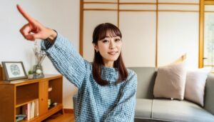 室内でチェック柄のトップスを着た若い人が指をさす