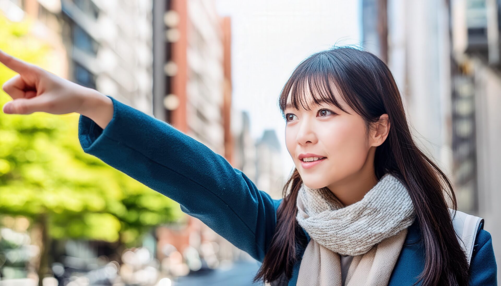 スカーフを巻いた若い人が街中で指をさす