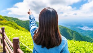 後ろ姿のデニムトップスを着た若い人が山の景色で指をさす