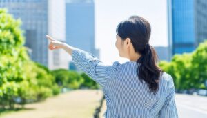 ストライプのトップスを着た後ろ姿の若い人が公園で指をさす