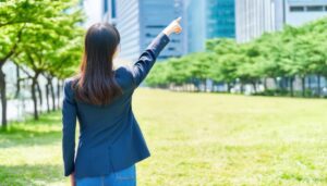 ネイビージャケットを着た後ろ姿の若い人が公園で指をさす