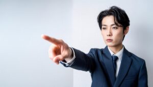 スーツ姿の人が白背景で正面を指す